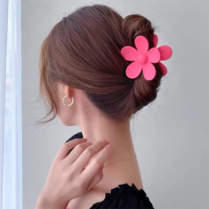 Detail of a matte pink flower hair claw clip securing a stylish bun on a model hair