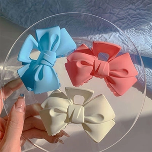 Détails de trois pinces à cheveux mates en forme de nœud en bleu, rose et crème