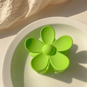 Detail of light green matte flower hair claw clip on a white ceramic dish