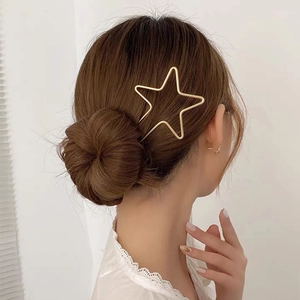 Détail d'un pic à cheveux étoile dorée porté sur une coiffure tressée élégante
