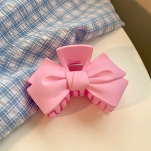 Détail de la pince à cheveux nœud rose avec fini mat et mécanisme à ressort en métal