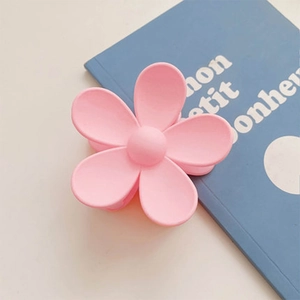 Detail view of pink matte flower hair claw clip on a book for daily hair styling