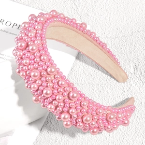 Close-up of pink padded headband with scattered faux pearls on elegant texture