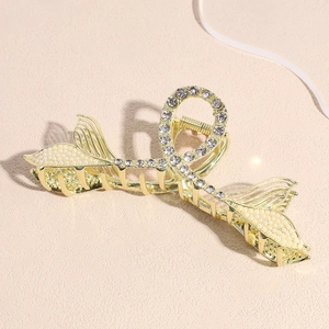 Elegant gold whale tail hair claw clip with pearls and rhinestones on sandy background