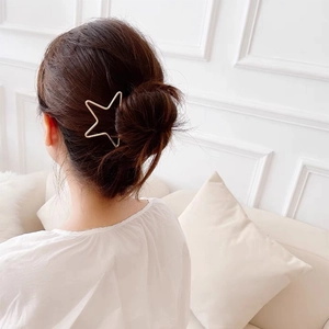 Détail d'une épingle à cheveux étoile creuse minimaliste en or sur un chignon femme