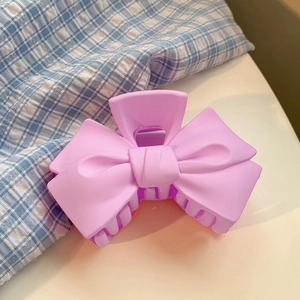 Gros plan sur une pince à cheveux mate rose et violette en forme de nœud élégant