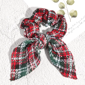 Detailed shot of Christmas plaid bow scrunchie with snowflake prints and tweed texture