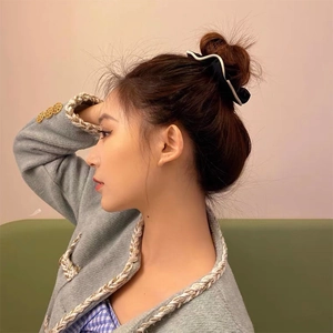 Elegant black satin scrunchie with white scalloped trim on a model's high bun hairstyle