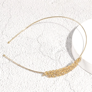 Detail shot of a slim golden leaf headband with sparkling rhinestones and feather accents
