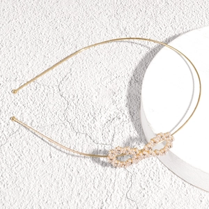 Detailed macro view of a gold metal headband with pearl infinity knot and rhinestones
