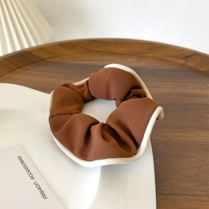 Detail of coffee brown scrunchie with cream contrast piping and ribbed fabric texture