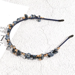 Detail of blue crystal beads and golden metal hollow balls on a slim headband