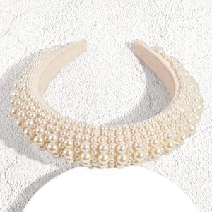 Détail macro du serre-tête rembourré beige avec des perles blanches artificielles denses