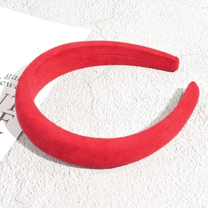 Vue détaillée du serre-tête rembourré en velours rouge avec texture daim sur fond en pierre