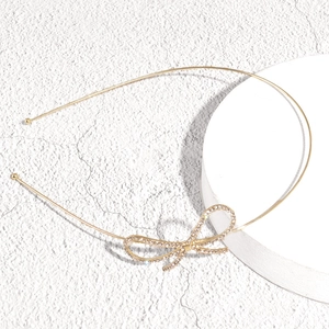 Close-up of golden metal headband with sparkling rhinestone bow on stone stand