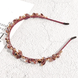 Detailed macro view of champagne crystal beads and golden alloys on a burgundy headband