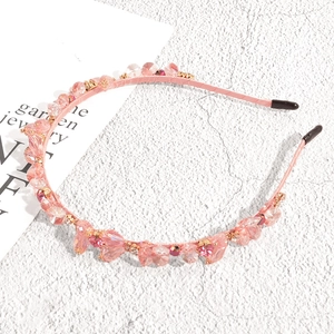 Detailed view of pink beaded headband with crystals and golden metal hardware details