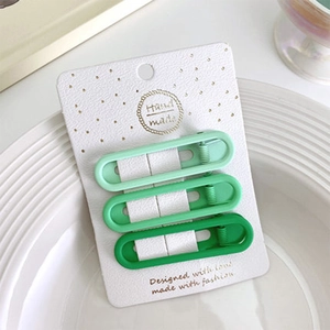 Dettaglio di tre fermagli per capelli verde sfumato opaco su confezione regalo
