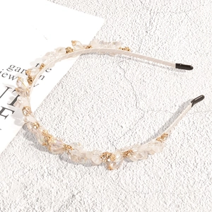 Detailed view of beige headband with crystal beads, pearls, and gold-set rhinestones