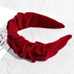 Détail d'un serre-tête en velours rouge avec texture plissée et design large élégant