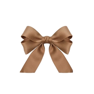 Detailed close-up of brown bow hair clip with textured shiny fabric and layered design