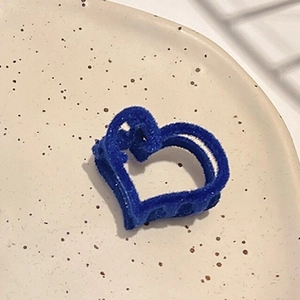 Vue détaillée de la pince à cheveux cœur floquée bleu Klein sur un plateau céramique