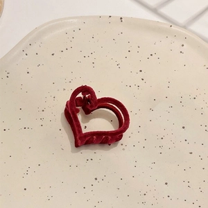 Détail macro d'une pince à cheveux en forme de cœur en velours rouge sur une assiette