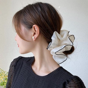 Close-up of beige organza oversized scrunchie on low bun with layered ruffles detail