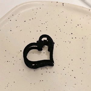 Gros plan d'une mini pince à cheveux cœur en velours noir sur un plateau en céramique