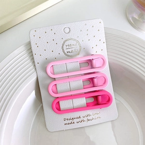 Dettaglio di tre mollette per capelli rosa opaco su cartoncino in un piatto bianco