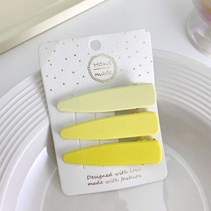 Set di tre fermagli per capelli gialli opachi presentati su cartoncino bianco