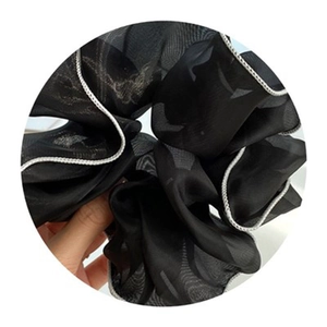 Elegant oversized black mesh hair scrunchie with white woven piping and sheer texture
