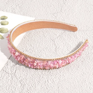 Detailed view of pink crushed stones and golden rhinestone edges on a baroque headband