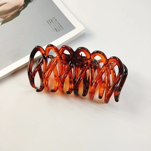Détail d'une pince à cheveux en résine ambrée au design en spirale sur fond de magazine
