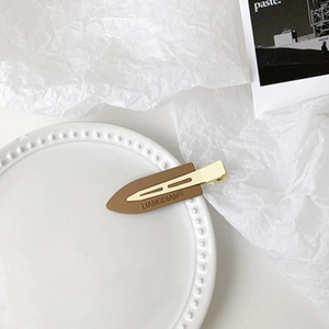Close-up of brown leather texture duckbill clip on elegant white pearl plate