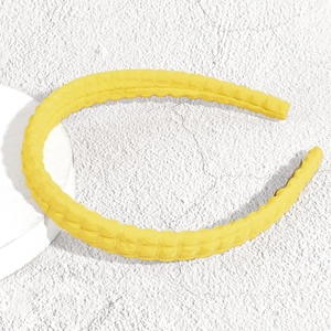 Vista dettagliata della fascia per capelli a quadretti gialli su piedistallo bianco