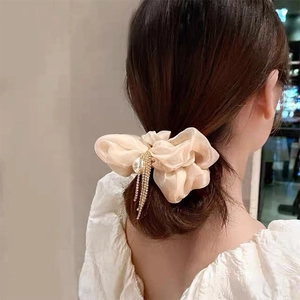 Detail of cream organza bow hair scrunchie with large pearl and rhinestone tassels