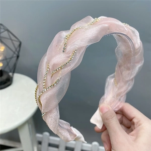 Détail d'un serre-tête en organza rose avec strass et dents de fixation antidérapantes