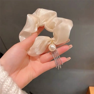 Detail of cream organza scrunchie with sparkling rhinestone tassels and elegant pearl