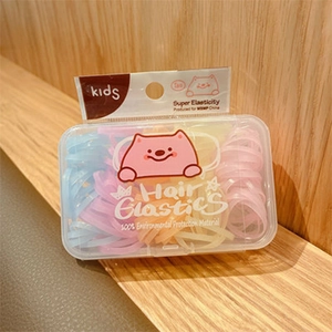 Close-up of colorful macaron hair elastics in a transparent box with cartoon cat design