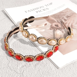 Baroque style gold headbands with luxury white pearls and red crystals set on a fashion magazine