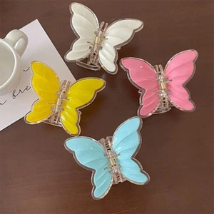 Detailed view of four colorful butterfly hair claws in pastel pink blue yellow and white