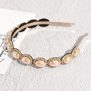 Detailed macro view of large faux pearls and rhinestones on a gold metal headband