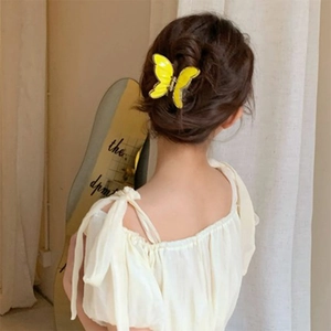 Detail showing a yellow butterfly hair claw clip worn on elegant dark brown hair updo