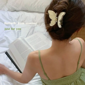 Detail of cream butterfly hair claw clip with gold trim on model with green dress