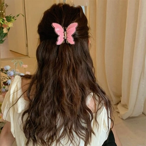Pink butterfly hair claw clip with double-layered wings on long wavy brown hair