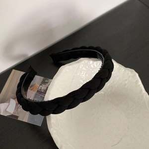 Close-up of black braided headband with anti-slip teeth on a white ceramic tray