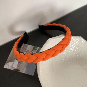 Detail view of orange braided headband featuring non-slip teeth for secure styling