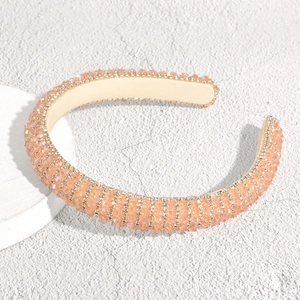 Nahaufnahme eines champagnerfarbenen Kristall-Haarreifs mit dichter Strass-Textur und Stoffbasis