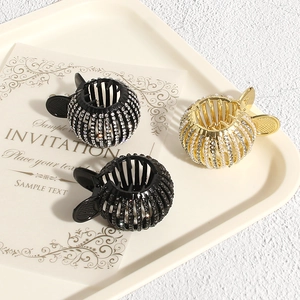 Detailed view of three decorative rhinestone and pearl bird nest hair clips on a tray